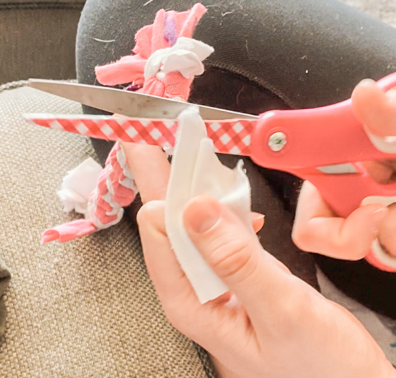 Lottie uses pink scissors to trim the end of her new toy